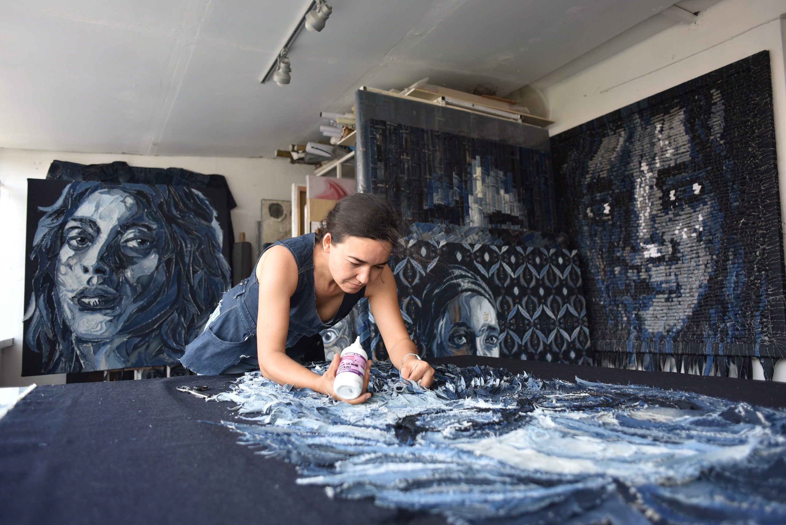 une artiste dans son atelier de collage avec des toiles derrières